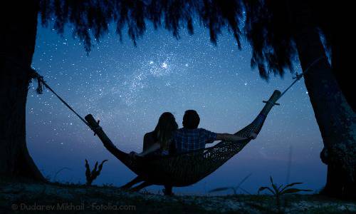 Couple ralaxing in a hammock and enjoying starry sky